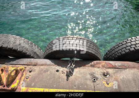 Alte Reifen hängen am Hafen von karakoy istanbul bosporus vorbei Mittel aus Metall Kette zum Verlegen neben etwas mit Türkis Farbe klares Wasser Stockfoto