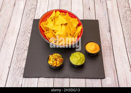 Schüssel mit knusprigen Maischips mit Cheddar-Frischkäse, Guacamole und Pico de gallo mit süßem Mais Stockfoto