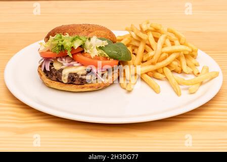 Rinderburger mit Salatsprossen, geschmolzenem Käse, roten Zwiebeln und Tomatenscheiben, garniert mit Pommes frites Stockfoto