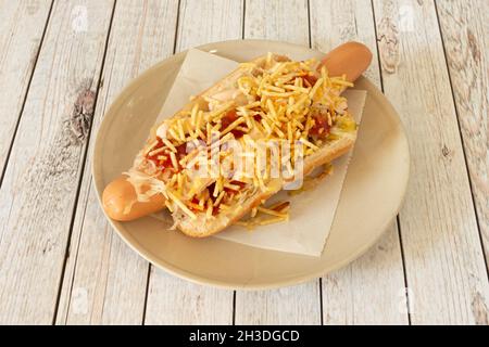 Hot Dog xxl mit Ketchup, Mayonnaise und Strohchips auf weißem Teller Stockfoto