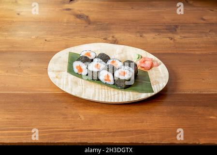 Acht Portionen Sushi Maki Roll gefüllt mit japanischem Reis mit Essig und norwegischem Orangenlachs gerollt mit Nori-Algen, Wasabi und Ginseng Stockfoto