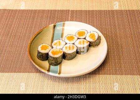 Acht Portionen Sushi Maki Roll gefüllt mit japanischem Reis mit Essig und norwegischem Orangenlachs gerollt mit Nori-Algen, Wasabi und Ginseng Stockfoto