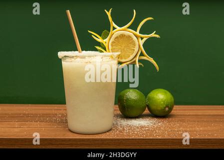 Gefrorene Zitronenlime Margarita mit Meersalz und Pappstrauch im Take Out Container mit dekorativem Zitronenkeil Stockfoto