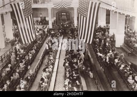 Ellis Island Port of New York und New Jersey am Hudson River. Ende des 19. Jahrhunderts und Anfang des 20. Jahrhunderts kamen die ersten Einwanderer, als sie in die USA kamen. Das Bild, das am 17 1923. märz aufgenommen wurde, und der große Warteraum für Menschen, die darauf warten, dass sie an der Reihe sind, um den Prozess der amerikanischen Staatsbürgerschaft zu beginnen. Ihre Papiere und Dokumente werden kontrolliert. 12 Millionen Menschen kamen auf ihrem Weg in die USA über Ellis Island und ca. 2% wurden der Einreise verweigert und nach Hause geschickt, wo sie herkamen. Stockfoto