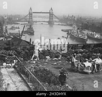 London in den 1930er Jahren. Blick über die Themse und die Tower Bridge vom Adelaide House. Im Vordergrund wird Tee serviert und auf der grünen Terrasse genossen. August 27 1935. Stockfoto