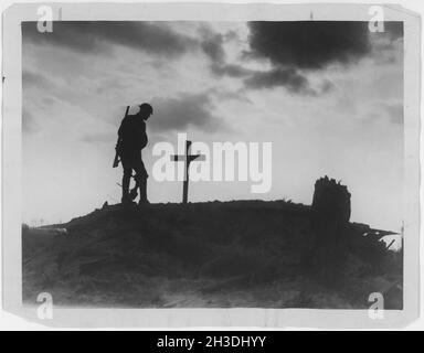 Erster Weltkrieg 1914-1918. Britischer Soldat und ein Grab, das mit einem Holzkreuz in Silhouette auf einem Hügel markiert ist. Stockfoto