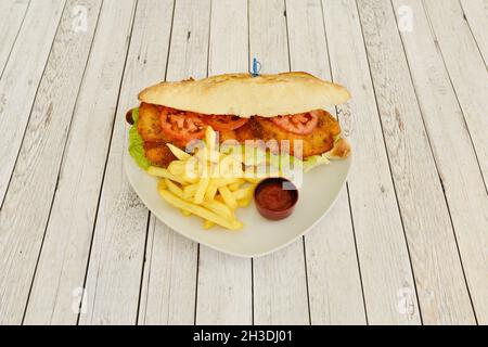 Sandwich mit Mailänder Rinderfilet mit Tomatenscheiben, Eisbergsalat, Pommes Frites und Ketchup-Sauce Stockfoto