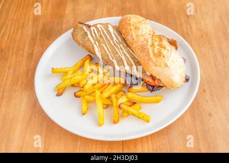 Argentinisches Milanga-Rindfleisch-Sandwich mit Salat und Tomaten, Mayonnaise-Sauce und Pommes frites Stockfoto