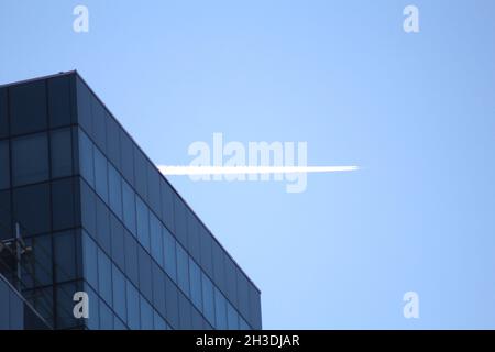 Die Flugbahn am blauen Himmel hinter dem Glasgebäude Stockfoto