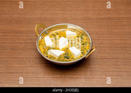 Weiße Schale Palak Paneer mit Spinat und Paneer-Käse in der Sauce in der dunklen Holzplatte Stockfoto
