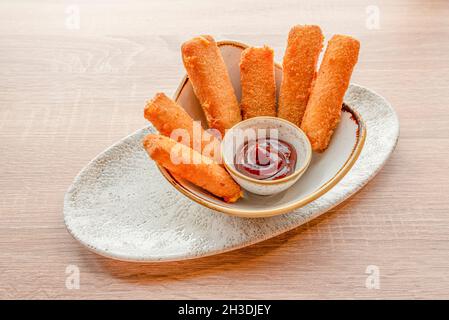 Köstliche Vorspeise aus Cheddar-Käse-Sticks mit Weizenmehl, Paniermehl und Ei mit Barbecue-Sauce zum Eintauchen beschichtet Stockfoto