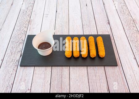 Vorspeise von Mozzarella-Sticks in Olivenöl auf einem schwarzen Schieferteller angeschlagen und gebraten Stockfoto