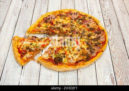 Pizza mit Hackfleisch, roten Paprika, geräuchertem Speck, Tomaten und Olegano mit Zwiebeln und Mozzarella-Käse Stockfoto