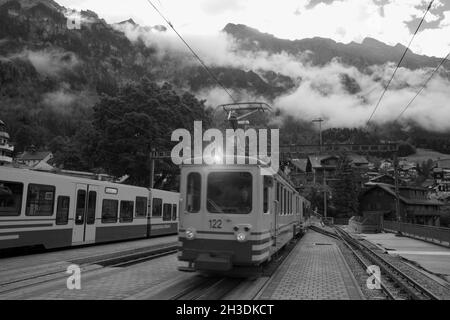 Bahnhof Wengen am Morgen mit Zügen bis zur Kleinen Scheiegg voll: Berner Oberland, Schweiz. Schwarz-Weiß-Version Stockfoto