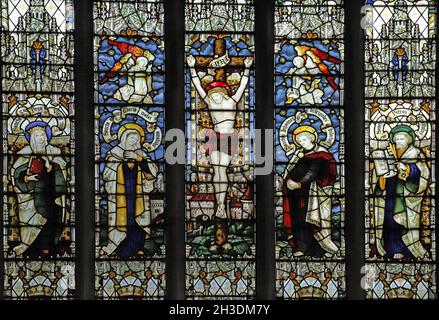 Buntglasfenster der Kempe Studios (1914) mit Darstellung der Kreuzigung jesu, flankiert von der St. Pega's Church, Peakirk, Northamptonshire Stockfoto