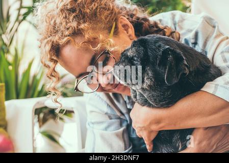 Glückliche Frau mit ihrem besten Freund Hund Pug in zärtlich Freizeit Aktivität zusammen zu Hause. Liebe Menschen und Tiere Lifestyle-Konzept. Erwachsene Hündin mit d Stockfoto