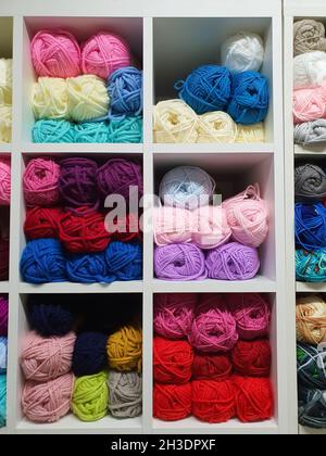Colorful yarns or balls of wool for knitting on shelves in the haberdashery shop. Knitwork handcraft concept Stockfoto