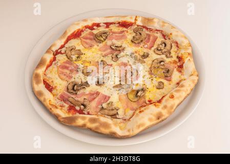 Italienische Pilzpizza mit Käse und geräuchertem Speck mit Oregano und Olivenöl, gekocht in einem Steinofen Stockfoto