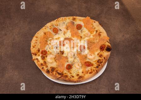 Italienische Pizza di Mare mit gekochten Garnelen, Kirschtomaten und geräuchertem Lachs mit Dill und Mozzarella-Käse Stockfoto