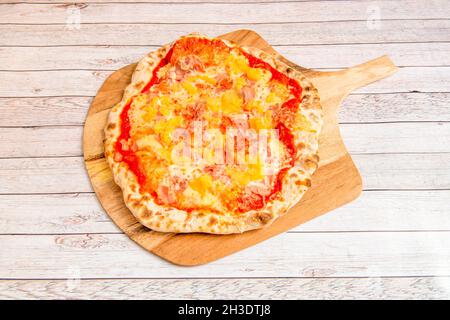 Hawaiianische Pizza mit Ananasstücken, Schinken, Mozzarella-Käse und Tomaten, die mit Weizenmehl gekocht werden Stockfoto