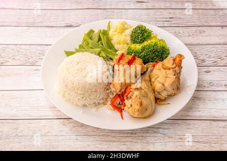 Soupy Chicken Eintopf mit grünen Bohnen, Blumenkohl und gekochtem Broccoli und weißem Reis auf weißem Teller Stockfoto