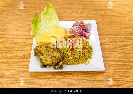 Portion Huhn mit Reis in peruanischer Sauce mit Kartoffeln a la huancaina und garnieren von lila Zwiebel mit Paprika Stockfoto