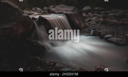 Langzeitaufnahme eines Stromes, der durch einen Wald läuft Stockfoto