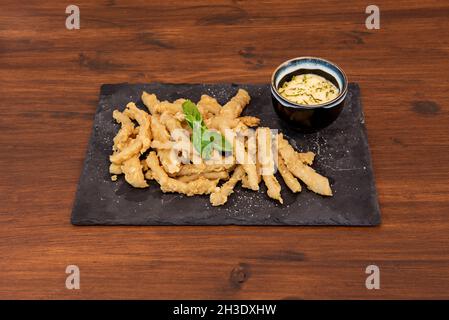 Typische spanische Tapa aus Tintenfisch-Rabas, mit Mehl und Ei zerschlagen, in Olivenöl gebraten und mit Aioli-Sauce serviert Stockfoto