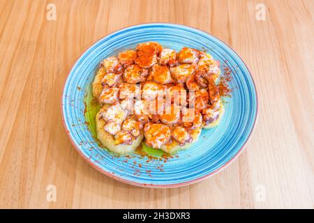 Beliebtes Rezept für Tapa Galicischer Oktopus mit Paprika aus La Vera, gekochten Kartoffeln und Olivenöl auf einem schönen blauen Teller Stockfoto