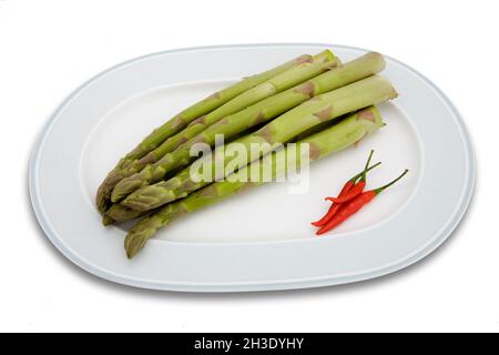 Gartensparagus, Sparrow Gras, Wildsparagus (Asparagus officinalis), Gartensparagus und Chilischoten auf einem Teller Stockfoto