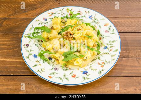 Italienisches Rezept für Ravioli gefüllt mit Birneneintopf, servieren mit Olivenöl, kalifornischen Nüssen und Rucola-Blättern. Stockfoto