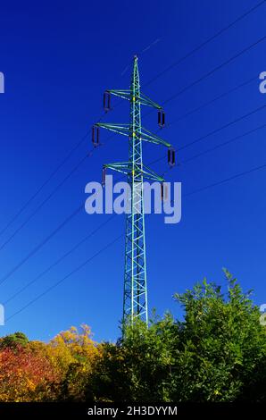 Hochspannungs-elektrische Türme und Linien mit schönem blauen Himmel über bunten Herbstbäumen. Eleetricity Türme. Hochspannungsübertragungsleitungen. Stockfoto