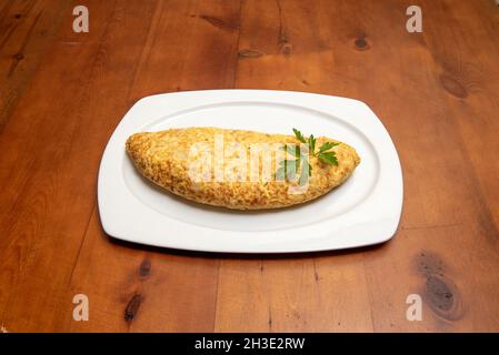 Ein halbes spanisches Kartoffelomelett mit Kabeljau wird in einem Tapas-Restaurant auf einem weißen Tablett serviert Stockfoto