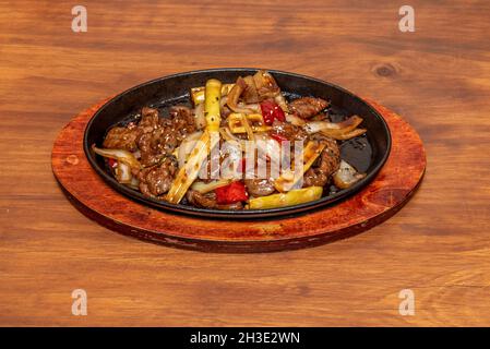 Chinesisches Rezept für Rindfleisch mit Bambus und Gemüse, im Wok mit Sojasauce und Sesam und Mohn auf dunklem Holztisch anbraten Stockfoto