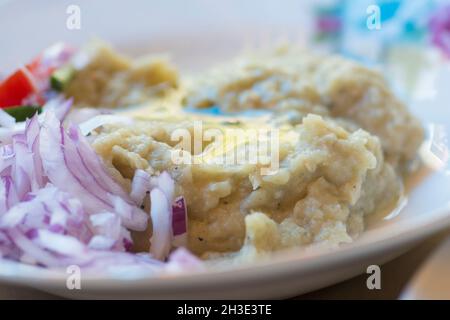 Nahaufnahme einer gegrillten Auberginen-Creme, serviert mit frischen roten Zwiebeln und Olivenöl Stockfoto