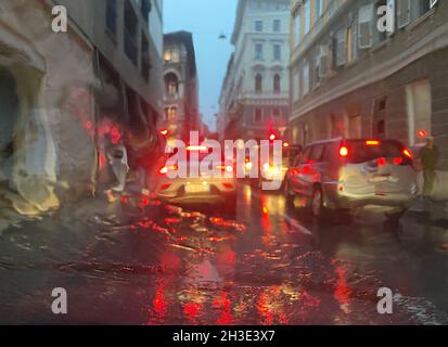 Regen auf der Straße mit Farbbeleuchtung an einem Verkehrsabend, Blick vom Auto auf der Straße, wenn es Regenzeit in der Stadt Wetter. Stockfoto