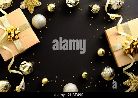 Luxuriöse goldene Weihnachtskugeln, Sterne, Geschenk und Konfetti auf dunkelschwarzem Tisch. Frohe Weihnachten und ein glückliches neues Jahr Bannerdesign, Grußkartenvorlage. Stockfoto