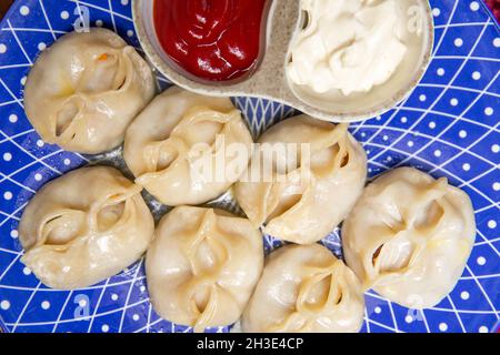 manti und Sauce auf einem blauen Teller Draufsicht Stockfoto