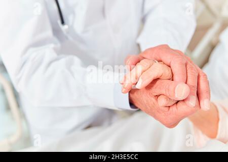 Der Arzt hält die Hand eines Patienten als Zeichen der Pflege und des Trostes | Modell-Zulassung verfügbar Stockfoto