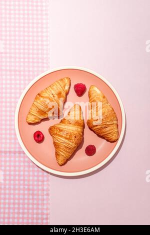 Von oben Zusammensetzung der mit frisch gebackenen süßen Croissants mit Beeren auf rosa Tisch gelegt serviert plattiert überzogen Stockfoto