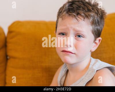Unglücklich erkrankte Kinder, die sich erkältet haben und zu Hause auf der Couch sitzen Stockfoto