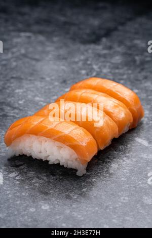 Ein ähnlich leckeres, traditionelles japanisches Sushi mit weißem Reis und frischem Lachs wird auf einem Marmortisch in einem hellen Raum serviert Stockfoto