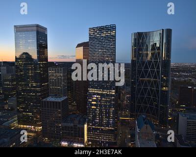 Schöne Luftaufnahme der westlichen Innenstadt von Calgary nach Sonnenuntergang mit den Silhouetten von beleuchteten Wolkenkratzern und orangefarbenen Himmel und Reflexionen. Stockfoto