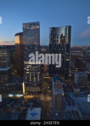 Wunderschöne Luftaufnahme der westlichen Innenstadt von Calgary nach Sonnenuntergang mit den Silhouetten von beleuchteten Wolkenkratzern und orangefarbenem Himmel mit Reflexionen. Stockfoto