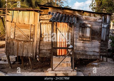 Außenansicht eines alten verlassenen Holzhauses, das auf felsigem Grund gegen grüne Bäume im Dorf auf São Tomé und Príncipe im Sommer aufgestellt wurde Stockfoto