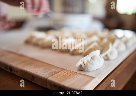 Von oben von rohen traditionellen Jiaozi Knödel auf Holz Schneidebrett in der Küche serviert Stockfoto