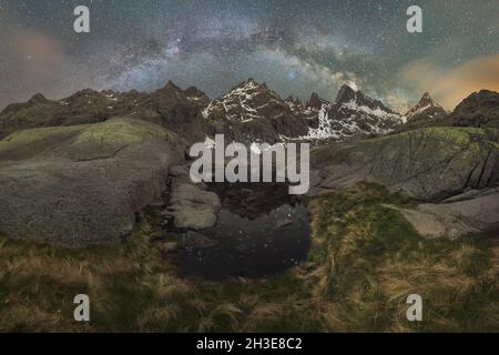 Laguna Grange See mit ruhigem Wasser im circo de Gredos cirque, umgeben von schneebedecktem Bergrücken vor dem sternenklaren Milchstraßenhimmel in Avila, Spanien Stockfoto