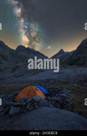 Panoramablick auf das Zelt am Seeufer gegen verschneite Berge unter dem wolkigen milchigen Himmel am Abend im Circo de Gredos cirque in Spanien Stockfoto