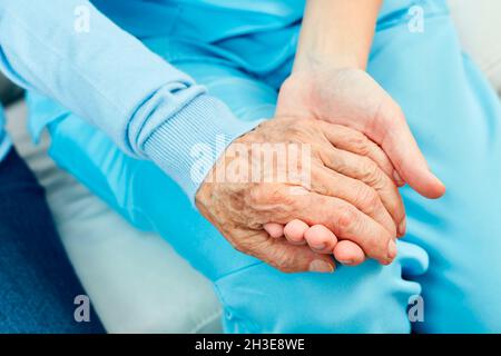 Der Pflegedienst oder die betreuende Krankenschwester halten die Hand eines älteren Bürgers als Trost | Modellgenehmigung zur Verfügung Stockfoto