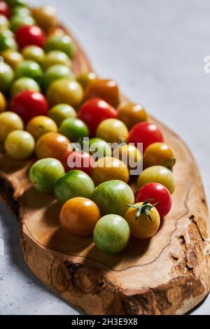 Reife rote und unreife Kirschtomaten, die während der Erntezeit auf dem Bauernhof gesammelt werden Stockfoto